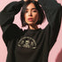 Christmas sweatshirt with "SEASONS SCREAMINGS, DARKLING" text arched over a skull wearing Santa hat. Bats, flowers, and ornate designs surround the skull in vintage-inspired style.